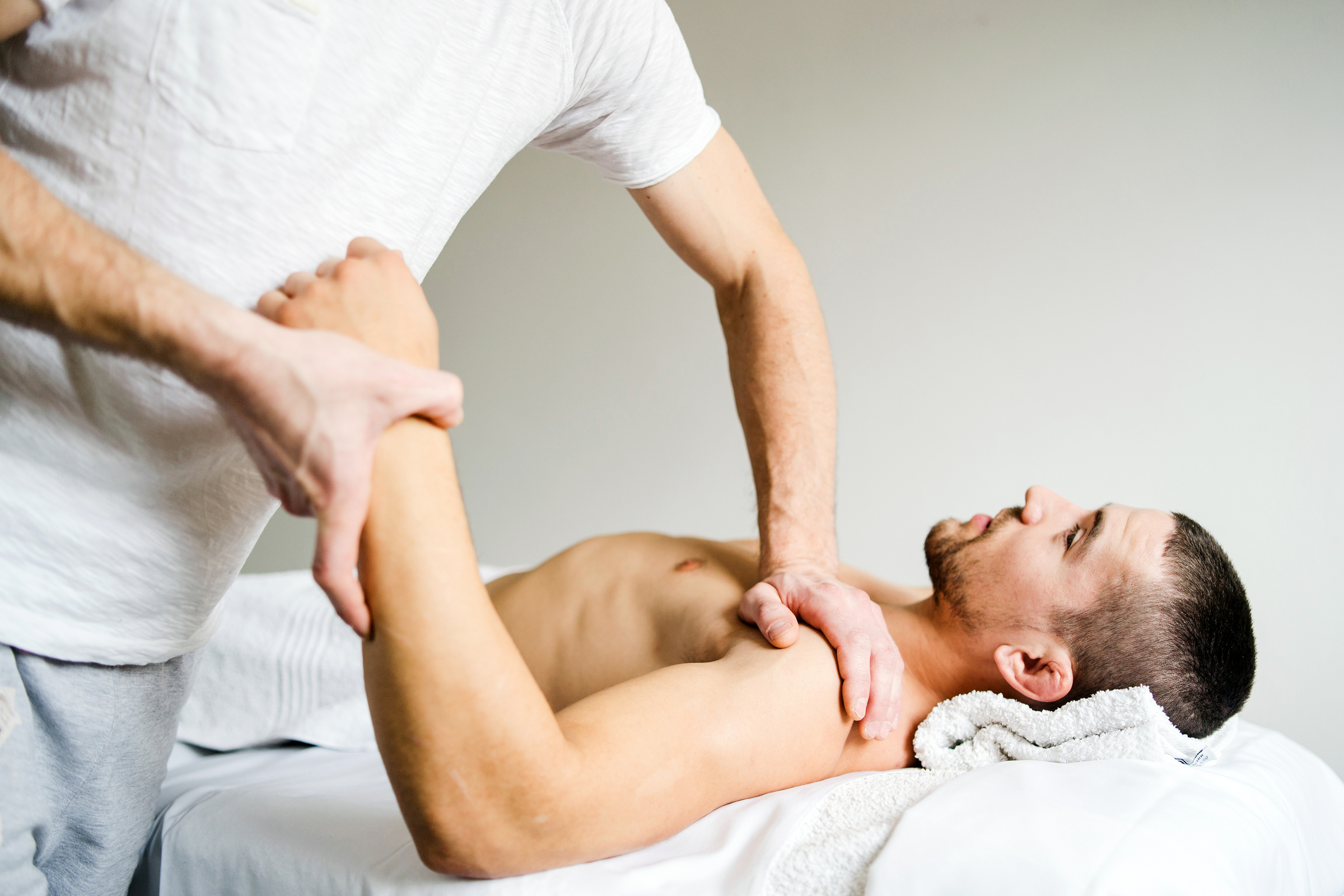 Male physio therapist giving sport massage to the young Man at the salon